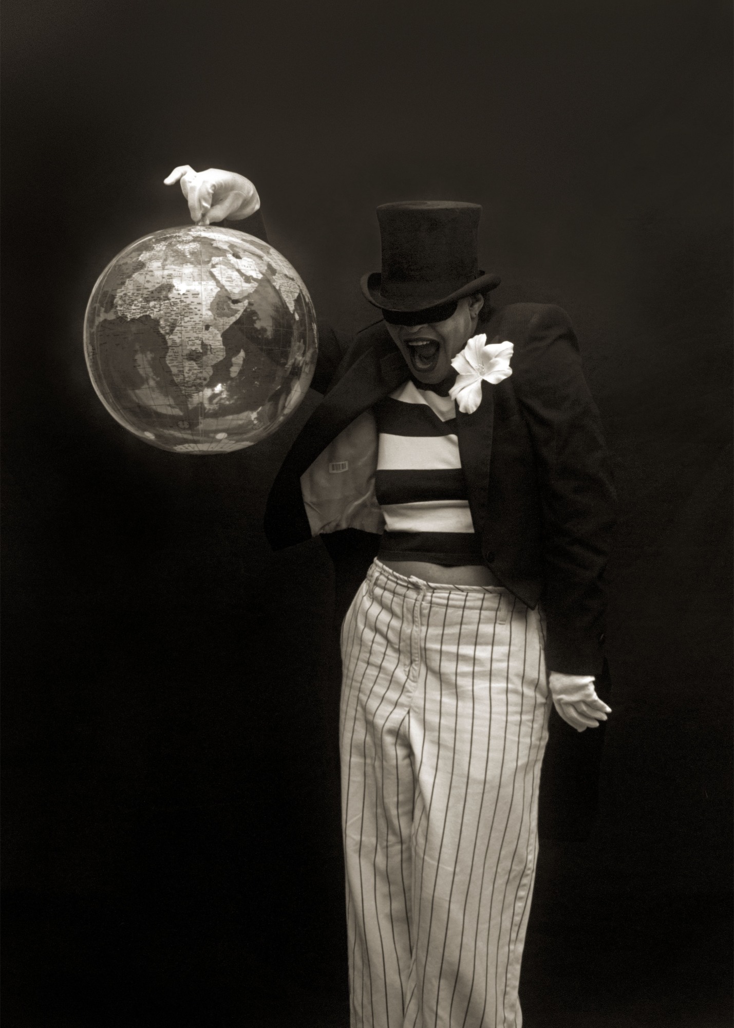 Artist Carrie Mae Weems in black tophat, eye mask, holding a globe in an outstretched white gloved-hand