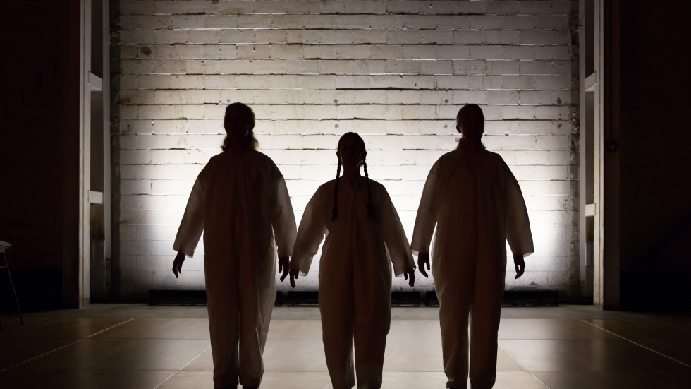 A trio of people in silhouette in front of a white brick wall