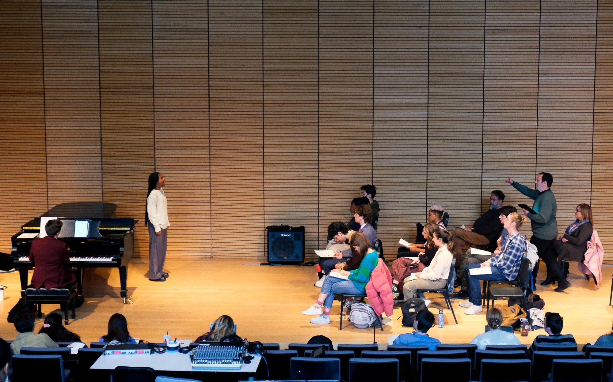 A class of students works with a musician on a stage