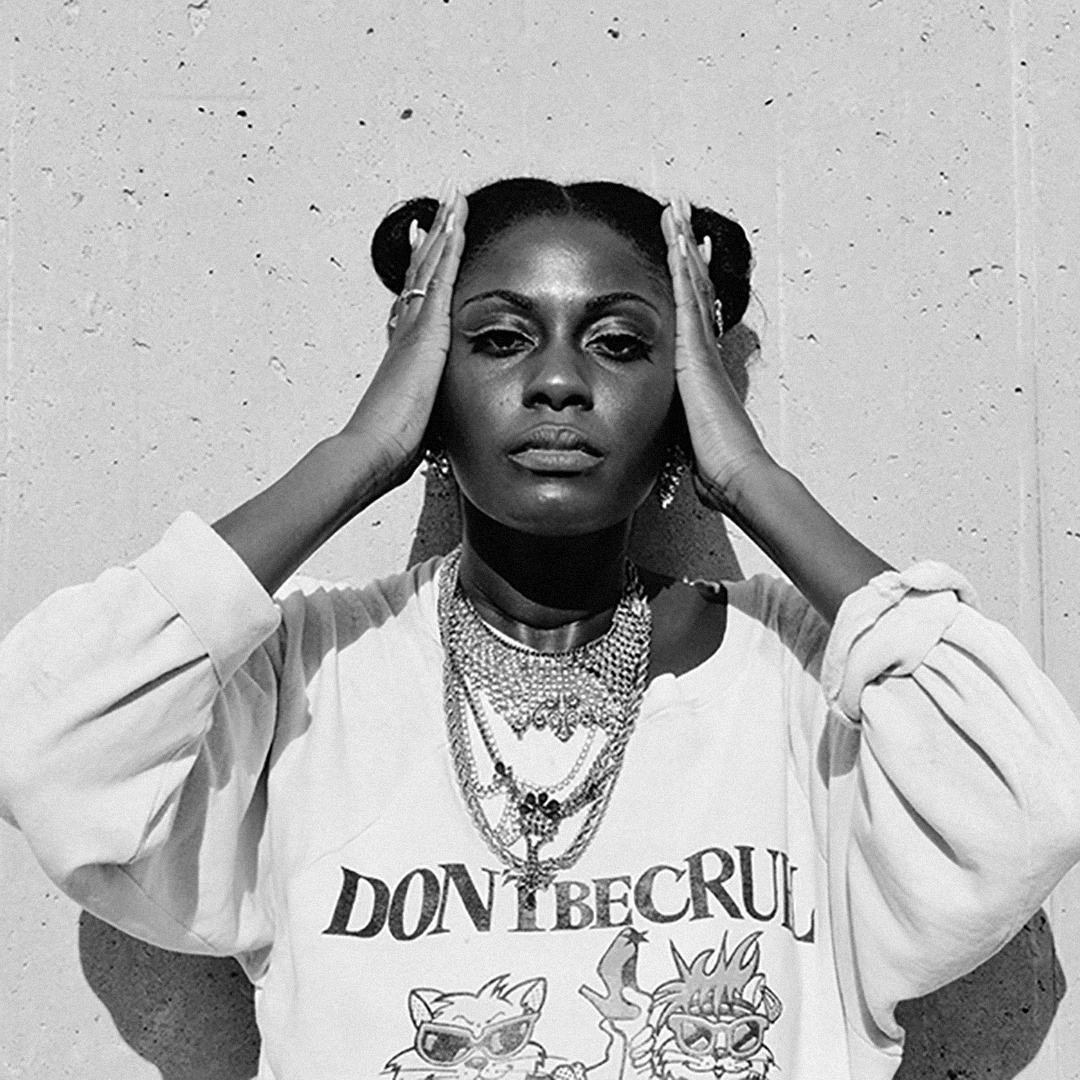 Enongo Lumumba-Kasongo holds her head and wears a Don't Be Cruel sweatshirt