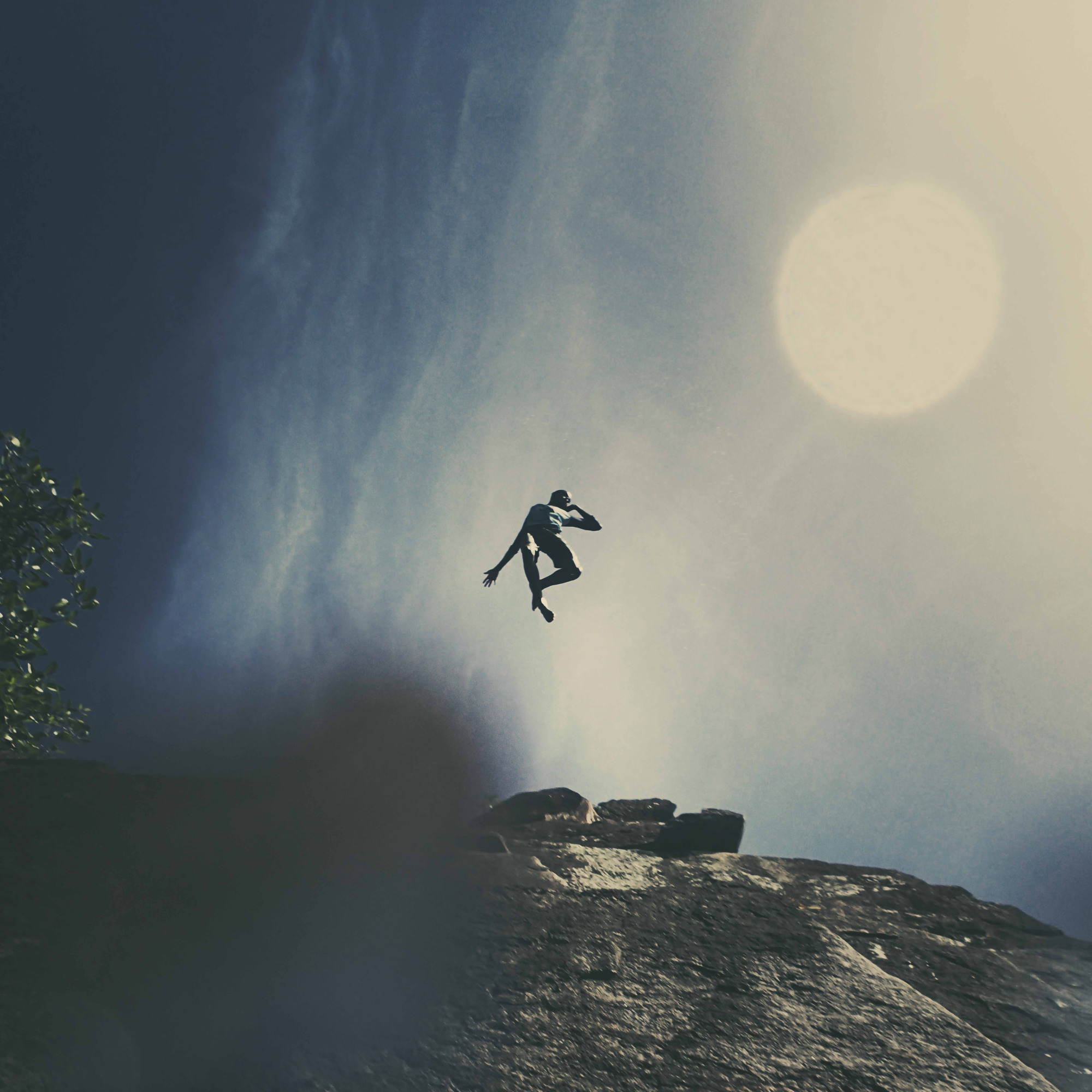 A person jumps in midair over rocky terrain with text reading exposure black queer visual constellations overlaid on the image