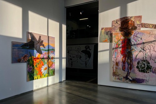A view of a gallery with large artworks on the walls and afternoon sunlight streaming in.