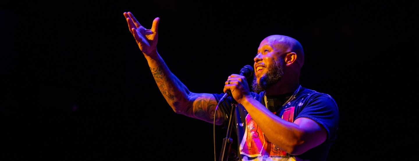 Chachi Carvalho on stage holding a microphone.