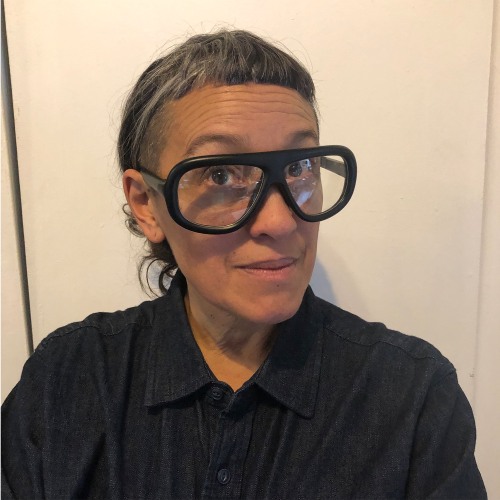 Julie Tolentino headshot wearing black with large black glasses