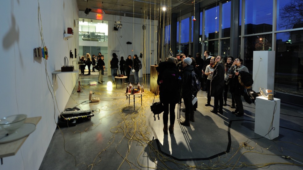 Peole at a gallery installation with chords hanging from the ceiling and coiled along the ground.