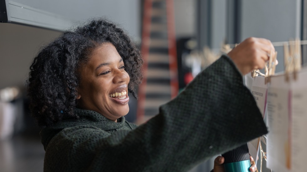 A woman pins a piece of paper to a clothesline