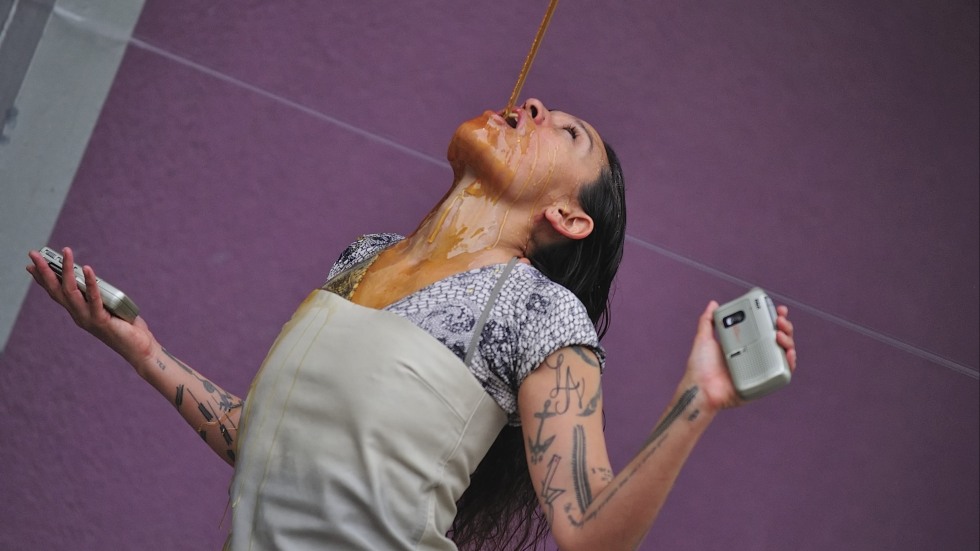 Julie Tolentino performing Honey in front of a purple wall