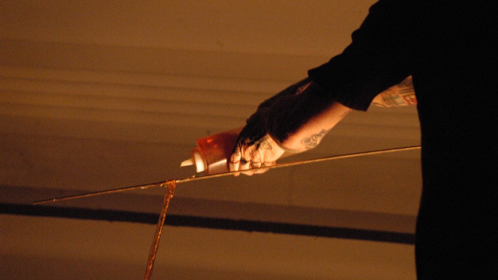 An outstretched arm dispensing honey down a thin rope.