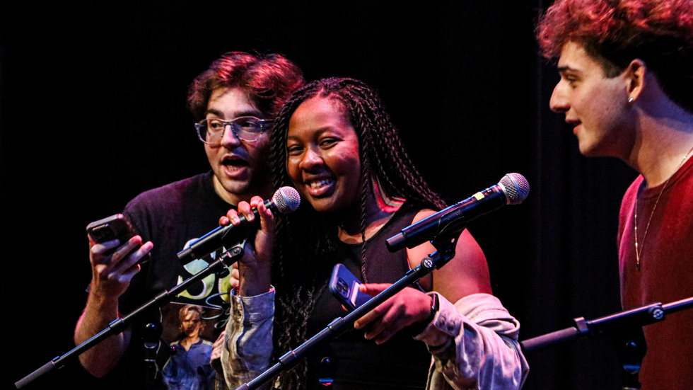 Three students perform on the Main Stage at The Lindemann during the 2025 Open Jam Sesh holding microphones and singing together