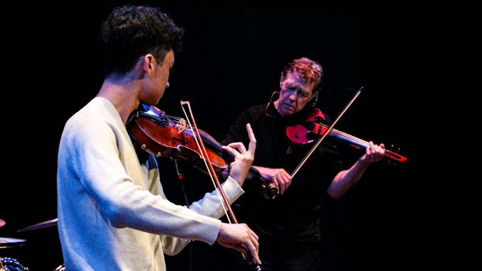 Two musicians play violins together on a stage during the 2025 Open Jam Sesh at The Lindemann Performing Arts Center