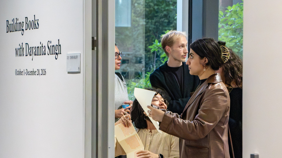 at left, a wall text reads building books with dayanita singh. at right, visitors to the exhibition fold the gallery note into a zine by following instructions out of frame.