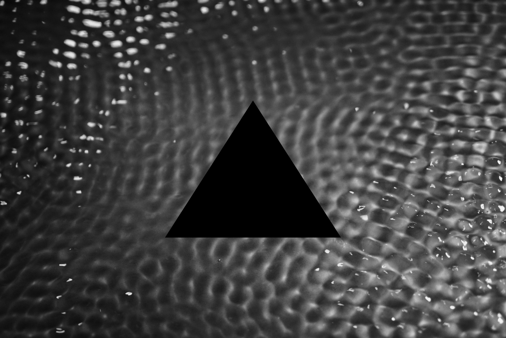 textured grayscale background with an upright black triangle in the center
